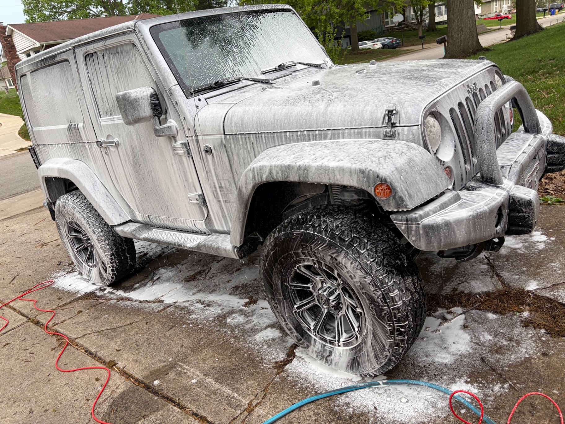 Lifted silver Jeep Wrangler covered in thick foam wash